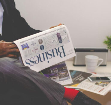 A businessman in a suit engaged in reading the newspaper's business section.